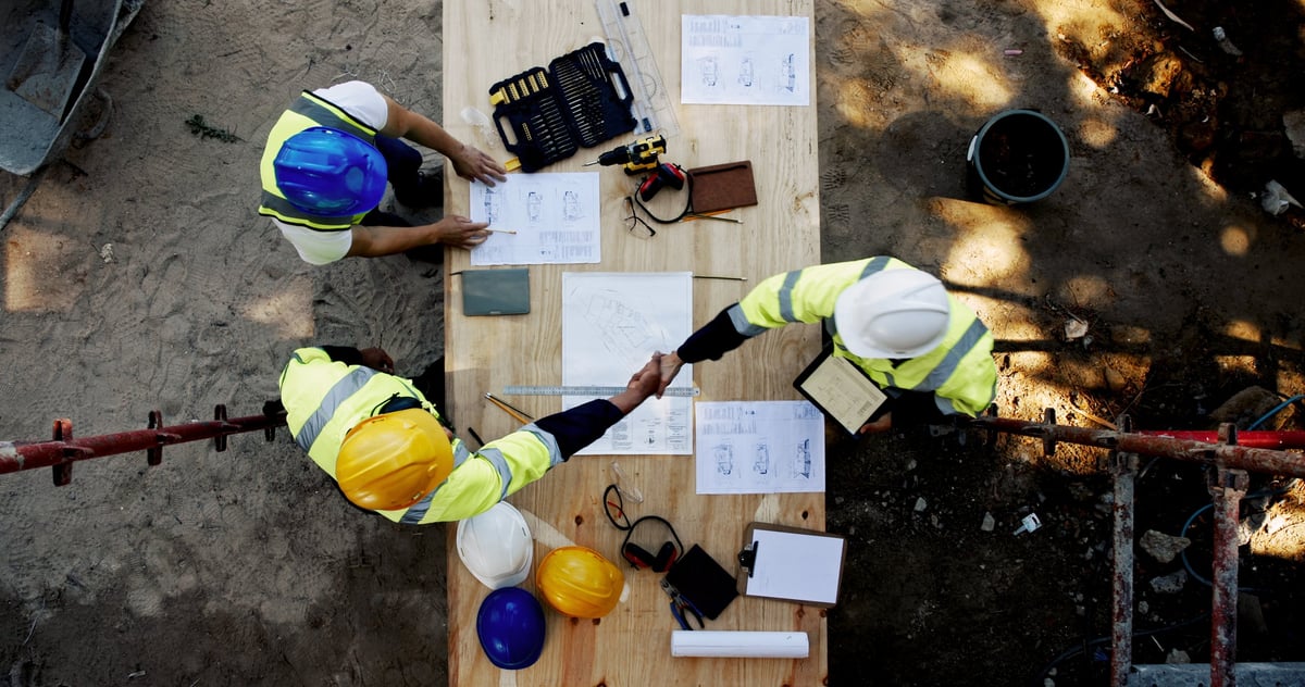 Blueprint and construction team shaking hands on agreement